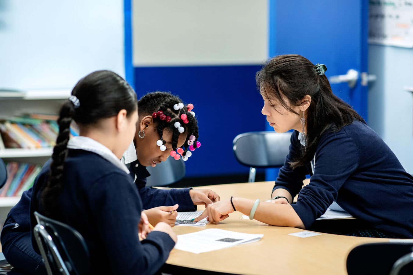 Teacher tutoring two scholars at a table