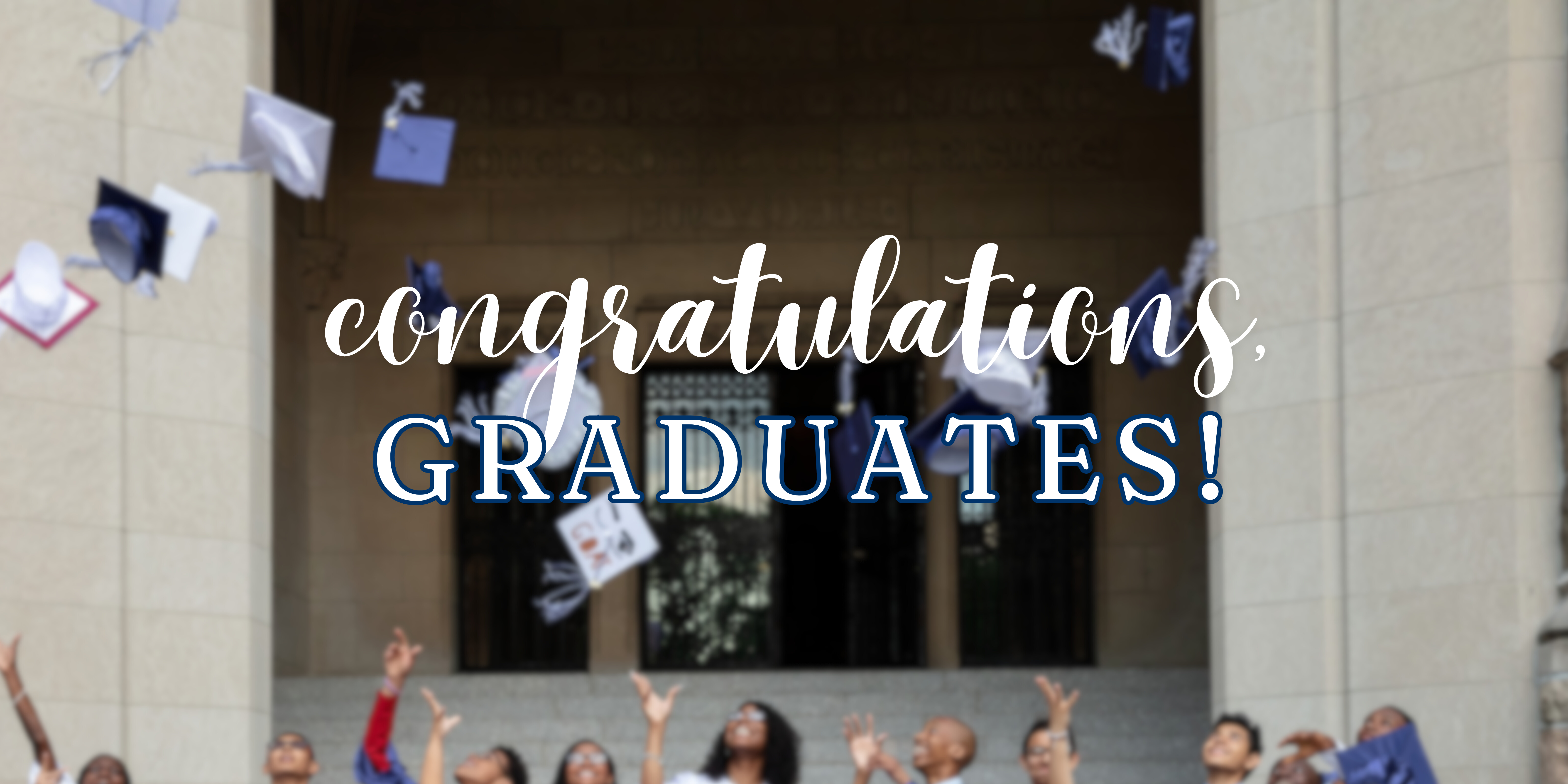 Scholars celebrating graduation under a congratulations banner