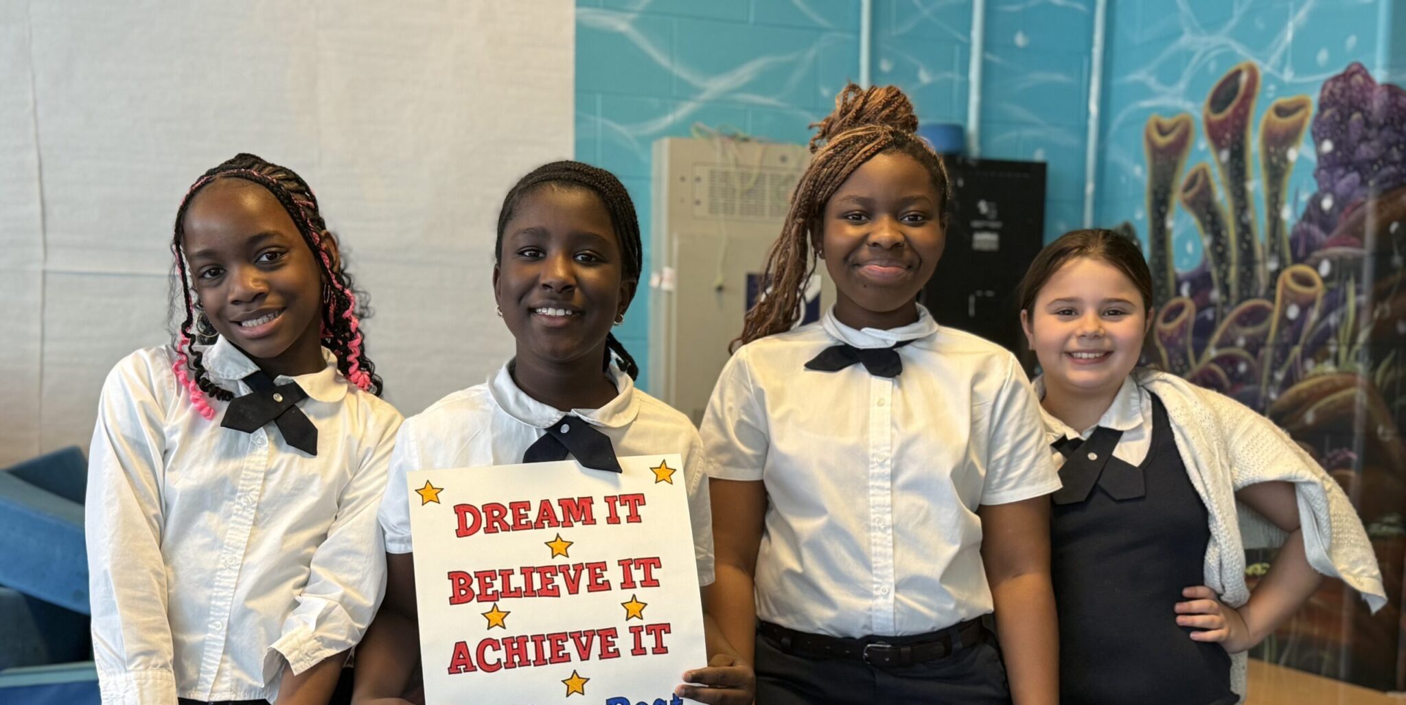Scholars holding a Dream It, Believe It, Achieve It sign
