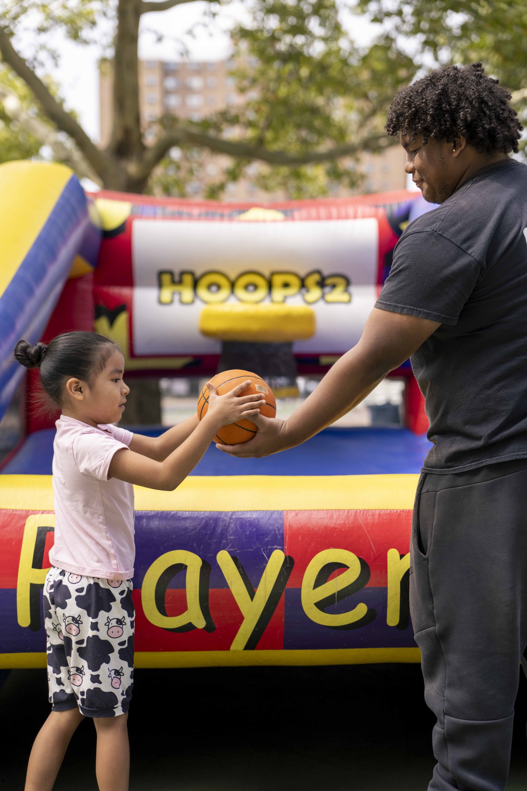 A child and adult share a basketball at a hoops game