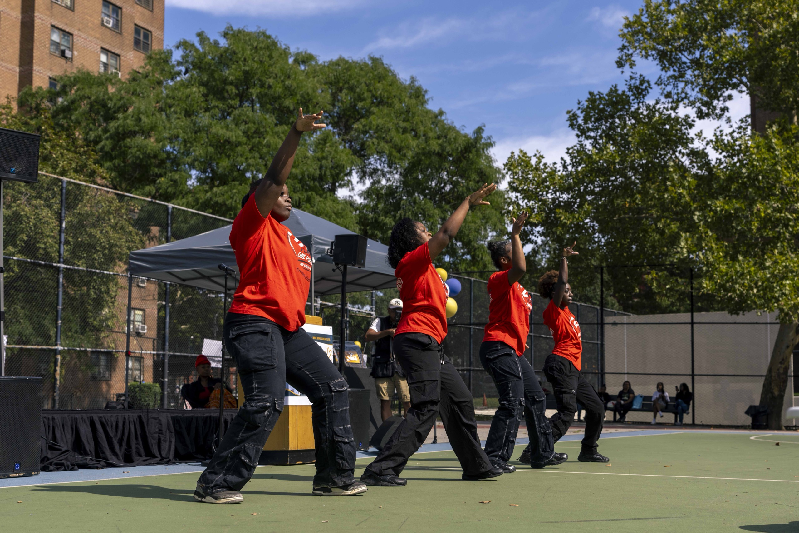 Young performers in red shirts dance on the School II court