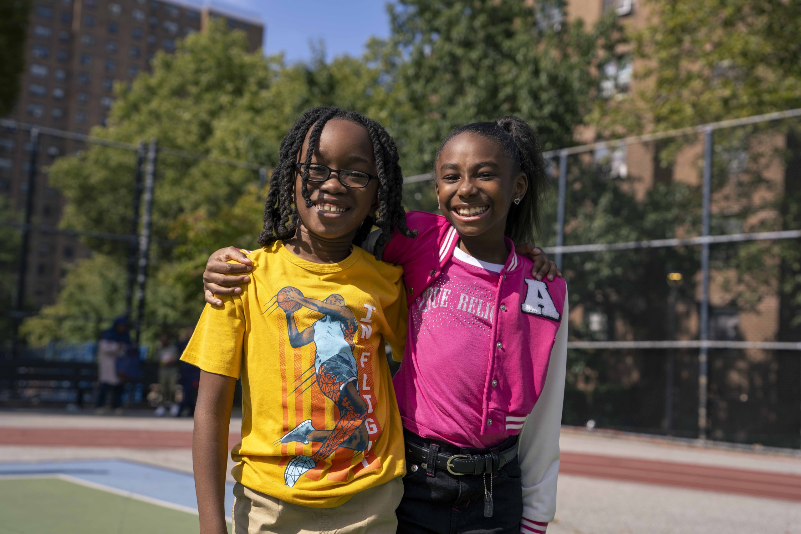 Two smiling children posing together on the court