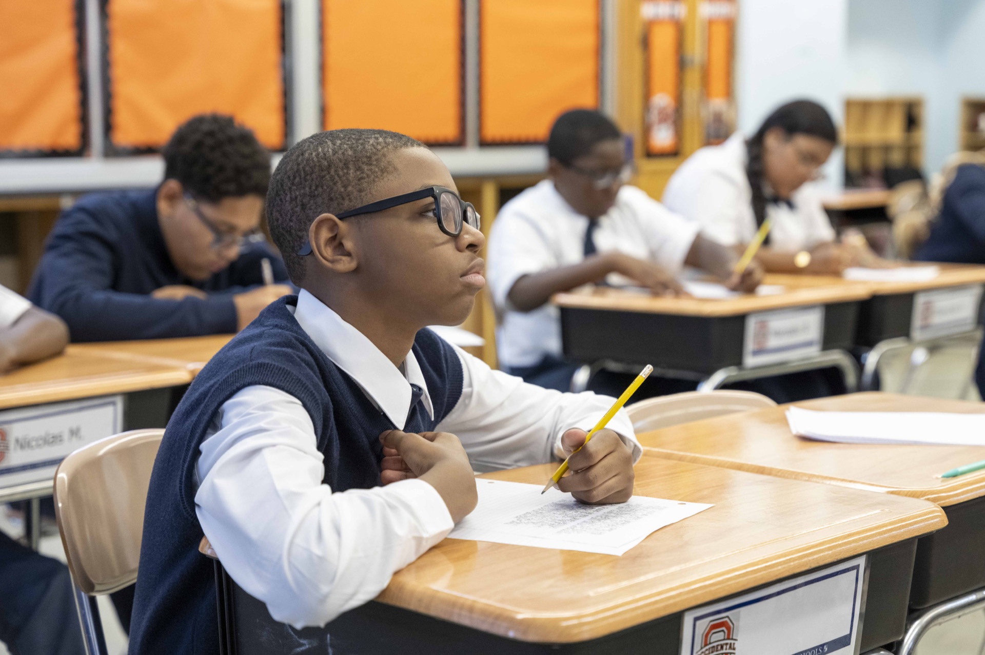 A Classical scholar works at a classroom desk with a pencil.