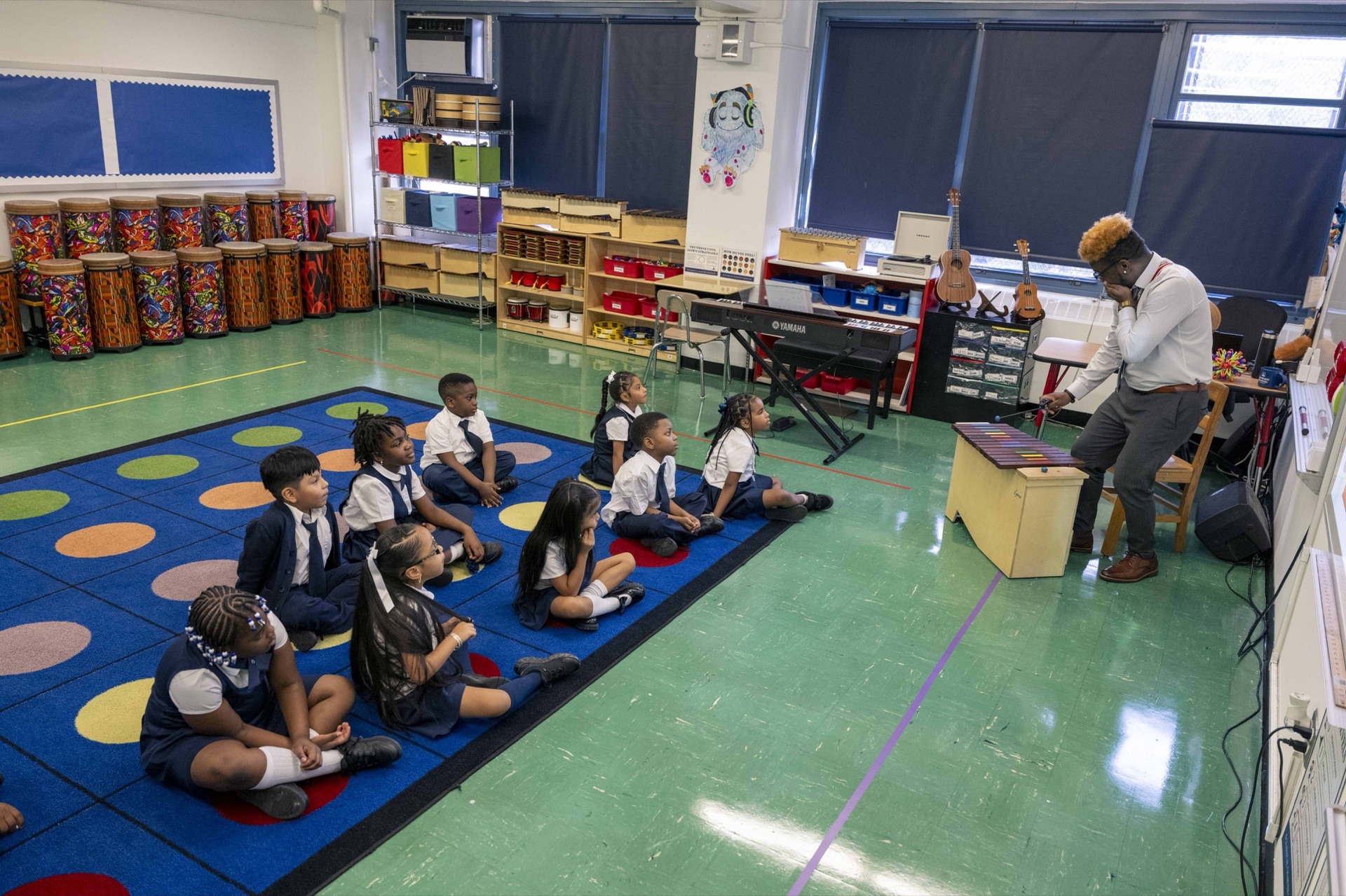 A music teacher demonstrates an instrument to Classical scholars.