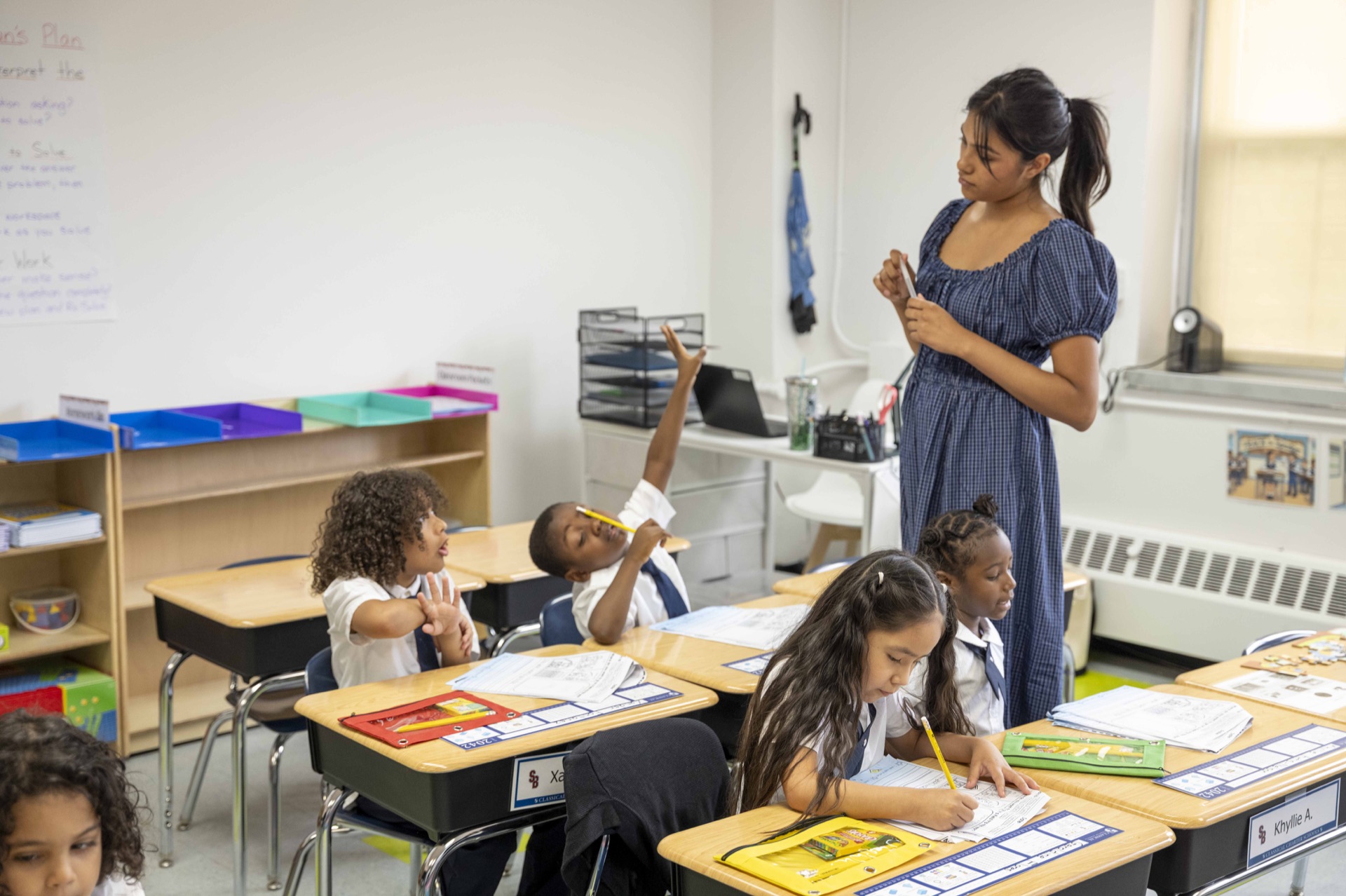 A Classical teacher supports young scholars during a classroom lesson.